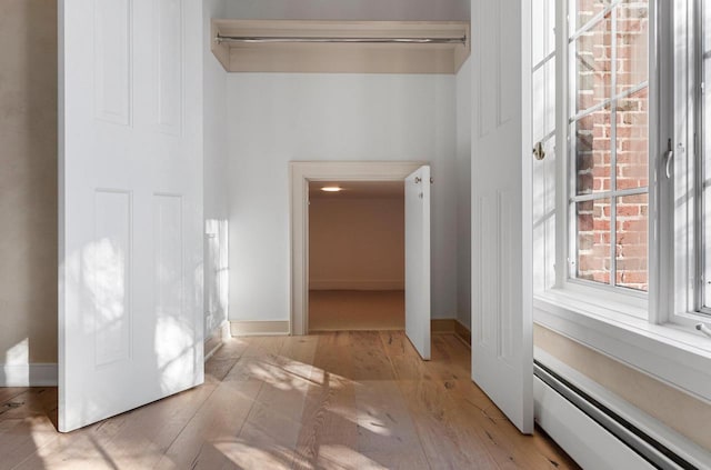 hall featuring baseboard heating and light hardwood / wood-style floors