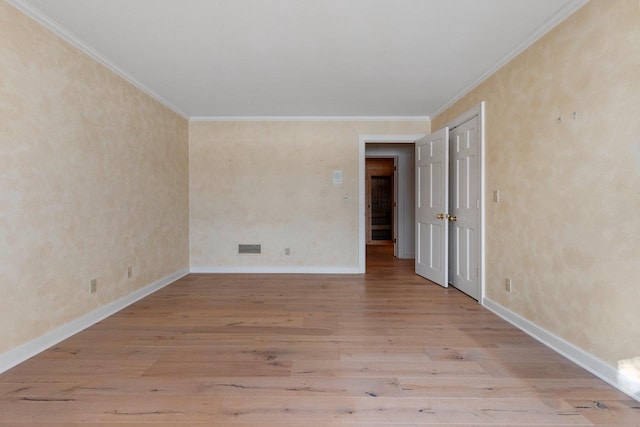 spare room featuring ornamental molding and light hardwood / wood-style flooring