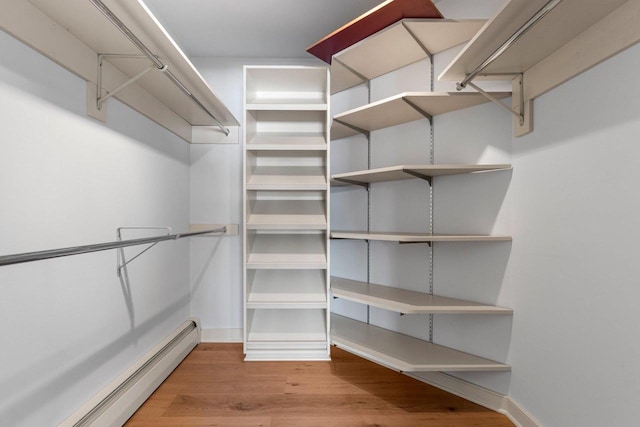 walk in closet featuring baseboard heating and light hardwood / wood-style flooring