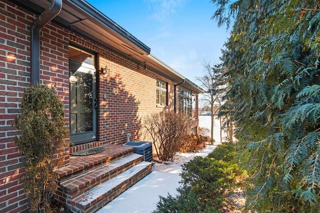 snow covered property with central AC