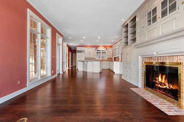 unfurnished living room featuring ornamental molding, a brick fireplace, dark wood-type flooring, and sink