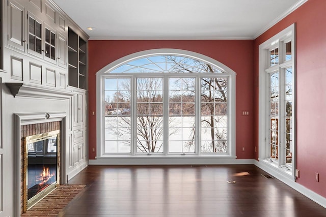 entryway with ornamental molding, a brick fireplace, and dark wood-type flooring