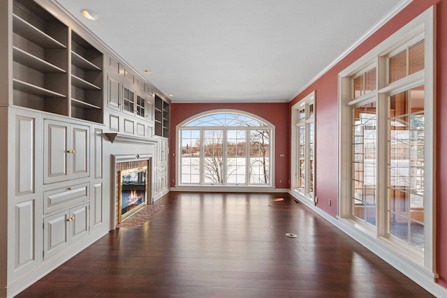 unfurnished living room featuring crown molding, dark wood-type flooring, built in features, and a fireplace