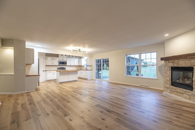 unfurnished living room with sink, a fireplace, and light wood-type flooring