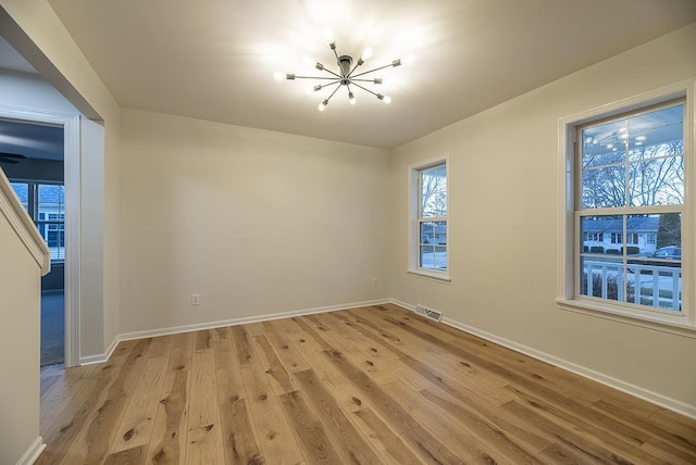 empty room with a chandelier and light wood-type flooring