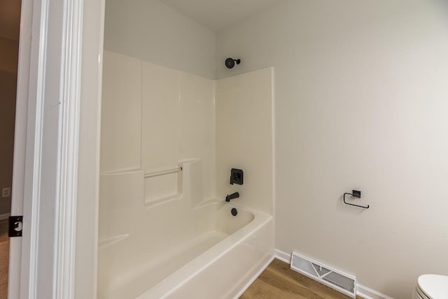 bathroom featuring hardwood / wood-style flooring, shower / bath combination, and toilet