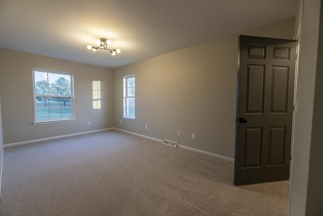 unfurnished room featuring light carpet and an inviting chandelier