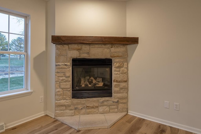 room details featuring wood-type flooring and a stone fireplace