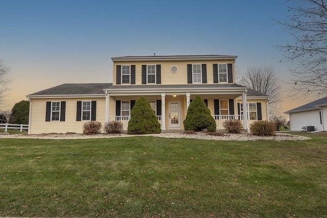 view of front facade featuring cooling unit, a lawn, and a porch