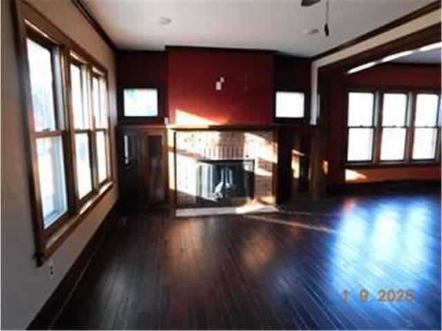 unfurnished living room with ceiling fan, ornamental molding, and dark hardwood / wood-style flooring