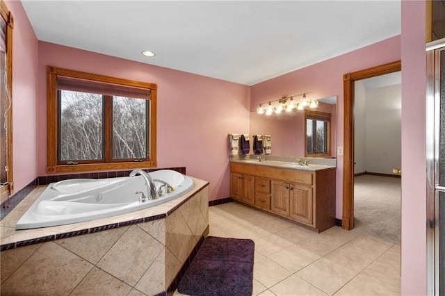 bathroom featuring tiled tub, vanity, and tile patterned flooring