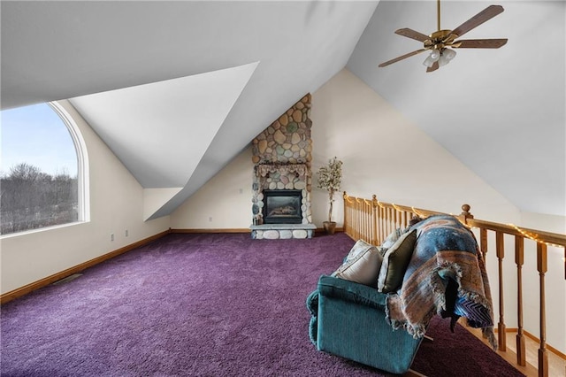 living room with vaulted ceiling, a stone fireplace, carpet floors, and ceiling fan