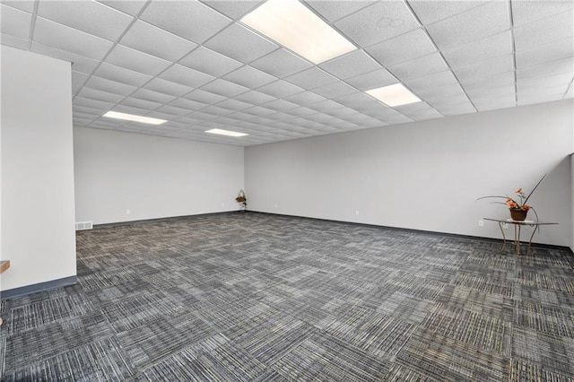 basement featuring a paneled ceiling and dark colored carpet