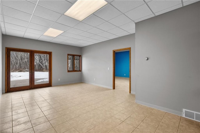 tiled spare room with a drop ceiling and french doors