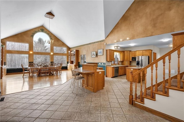 kitchen with a breakfast bar area, a center island, high vaulted ceiling, stainless steel fridge with ice dispenser, and light tile patterned floors