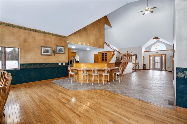 dining area with ceiling fan, high vaulted ceiling, and light hardwood / wood-style flooring