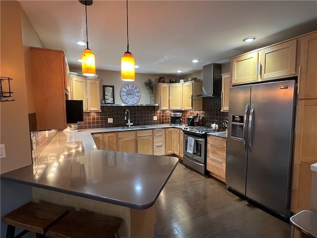 kitchen featuring wall chimney exhaust hood, sink, decorative light fixtures, appliances with stainless steel finishes, and kitchen peninsula