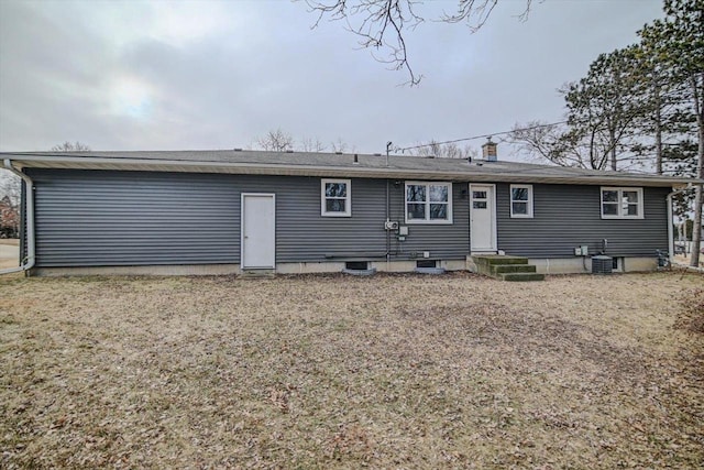 rear view of house featuring central AC unit and a lawn