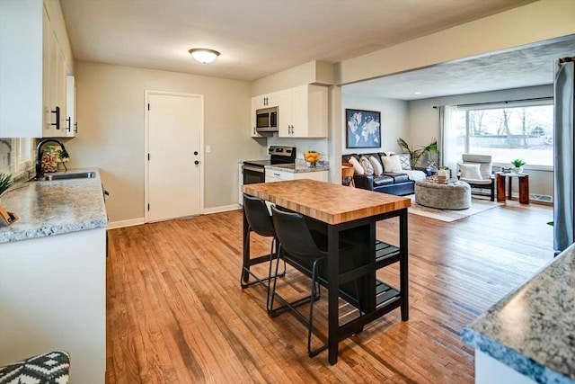 kitchen with white cabinetry, sink, light hardwood / wood-style flooring, and stainless steel appliances