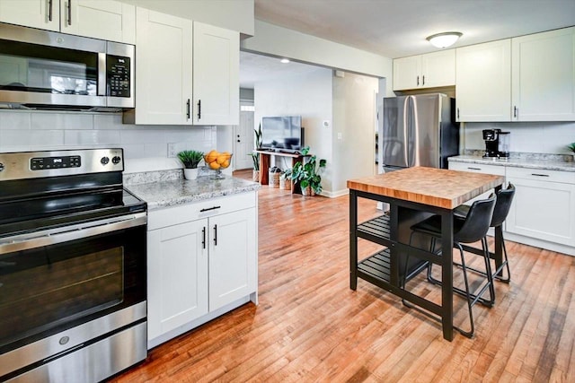 kitchen featuring stainless steel appliances, light stone countertops, and white cabinets