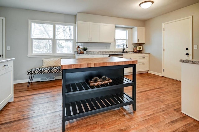 kitchen featuring sink, white cabinetry, wood counters, stainless steel dishwasher, and light wood-type flooring