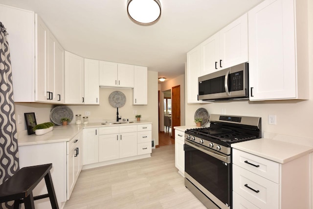 kitchen with stainless steel appliances, sink, and white cabinets