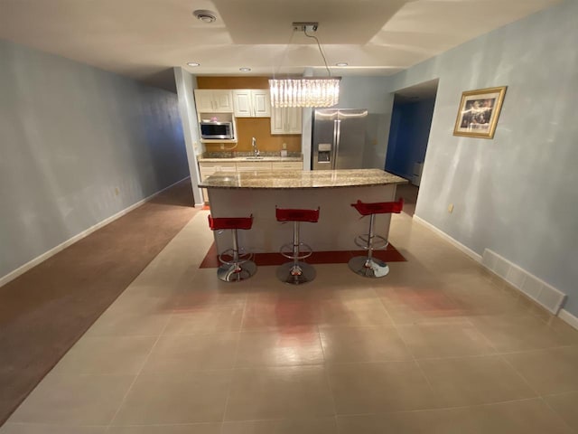 kitchen with decorative light fixtures, a breakfast bar area, a center island, light stone counters, and stainless steel appliances