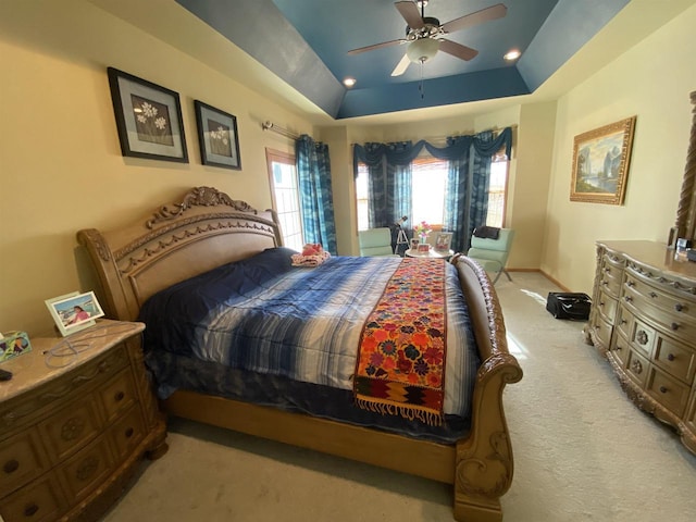 carpeted bedroom with ceiling fan and a tray ceiling