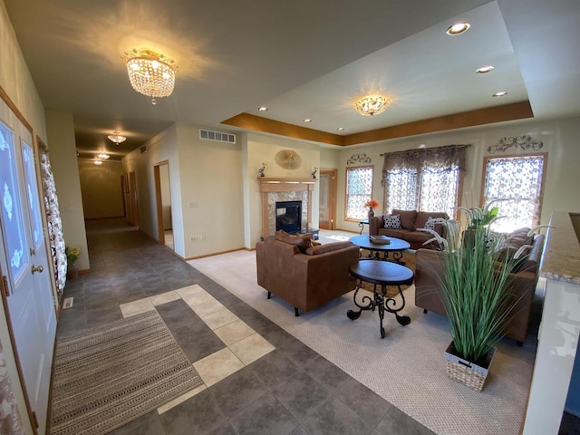 carpeted living room with an inviting chandelier, a fireplace, a healthy amount of sunlight, and a tray ceiling