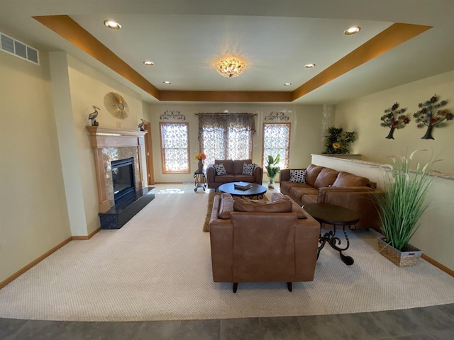 living room with carpet flooring, a high end fireplace, and a tray ceiling