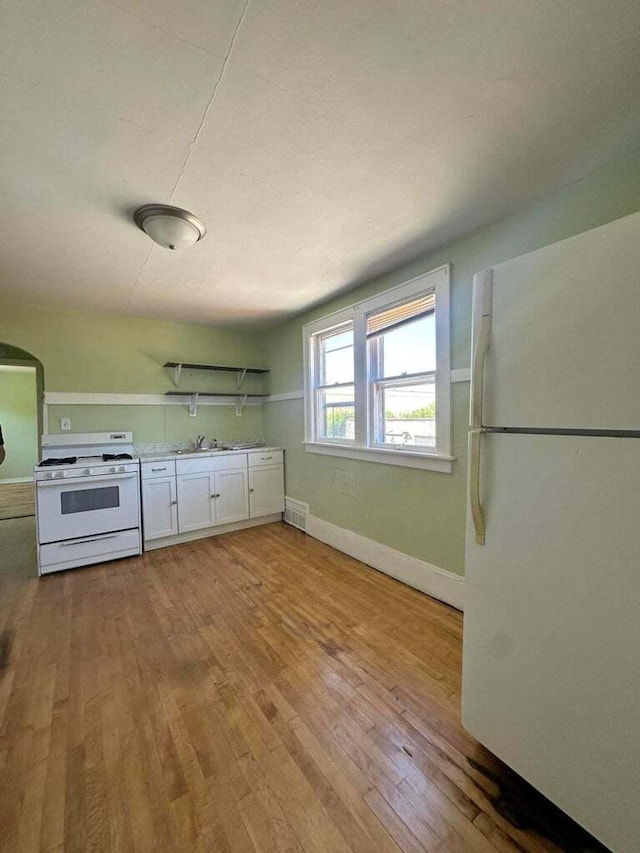 kitchen with white cabinetry, white appliances, sink, and light wood-type flooring