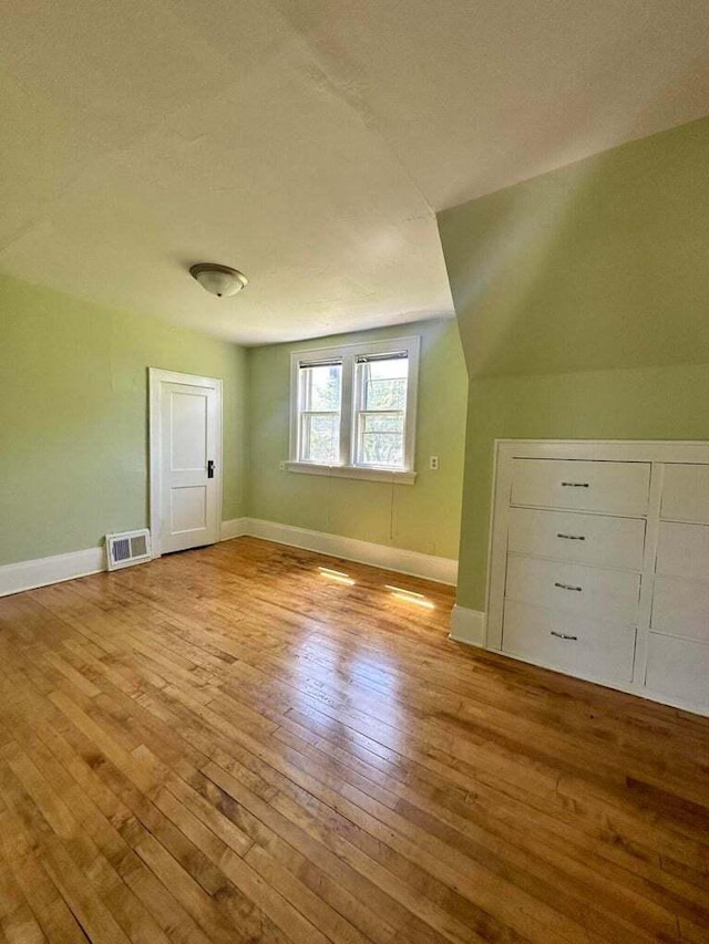 additional living space featuring vaulted ceiling and light hardwood / wood-style flooring