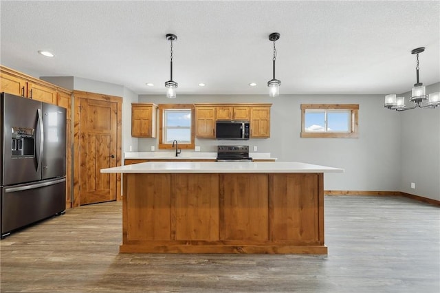 kitchen with stainless steel electric range oven, a kitchen island, decorative light fixtures, fridge with ice dispenser, and light wood-type flooring