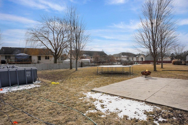 view of yard with a trampoline, a patio area, a covered pool, and an outdoor fire pit