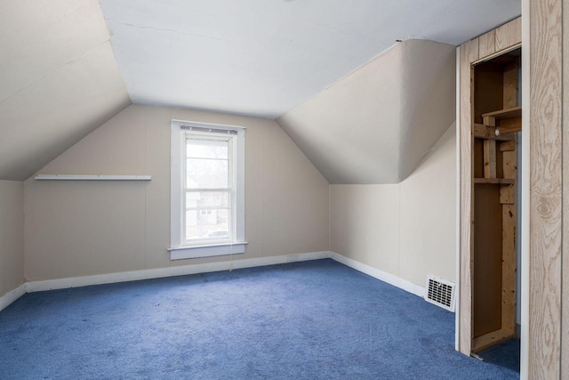 additional living space with vaulted ceiling and dark colored carpet