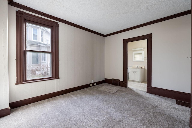 unfurnished room featuring ornamental molding, light colored carpet, and a textured ceiling