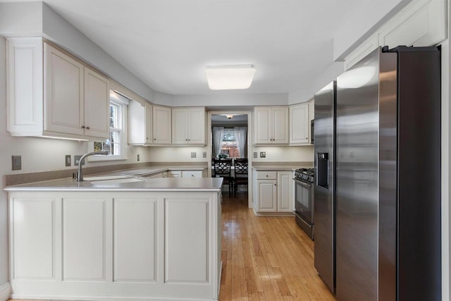 kitchen featuring stainless steel refrigerator with ice dispenser, sink, black range with gas stovetop, and a healthy amount of sunlight