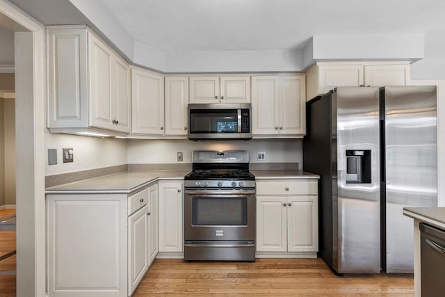 kitchen with stainless steel appliances, white cabinets, and light wood-type flooring