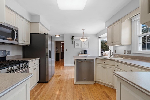 kitchen with sink, decorative light fixtures, light hardwood / wood-style floors, and appliances with stainless steel finishes