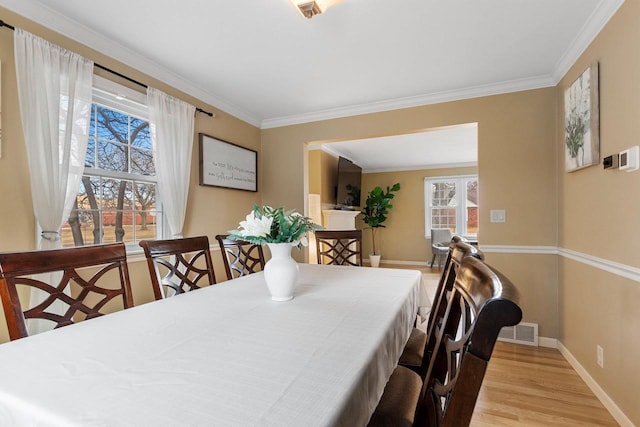 dining space with crown molding and light hardwood / wood-style flooring