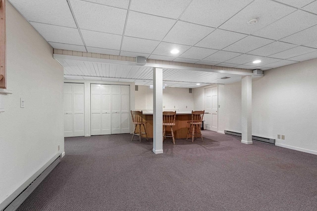 basement featuring dark colored carpet, indoor bar, and baseboard heating