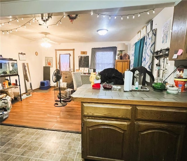 kitchen featuring ceiling fan, dark brown cabinetry, and tile countertops