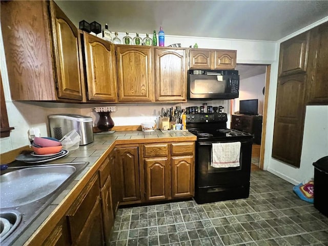 kitchen with sink, tile counters, and black appliances