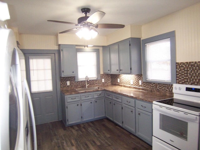 kitchen with white electric range, stainless steel refrigerator, sink, backsplash, and dark hardwood / wood-style flooring