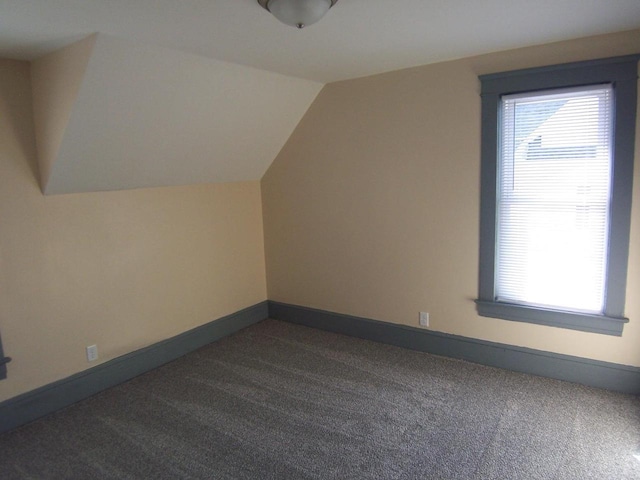 additional living space featuring dark colored carpet and vaulted ceiling