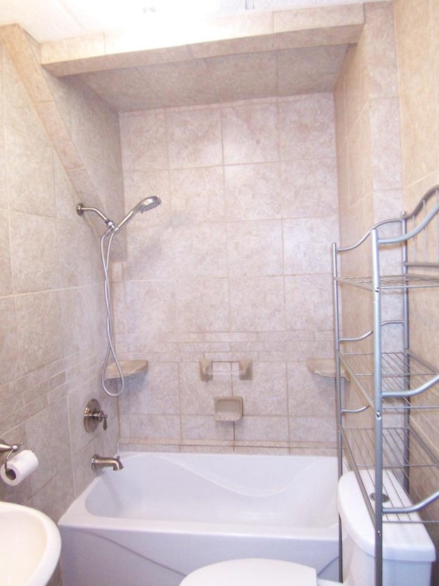 bathroom featuring tiled shower / bath combo and toilet