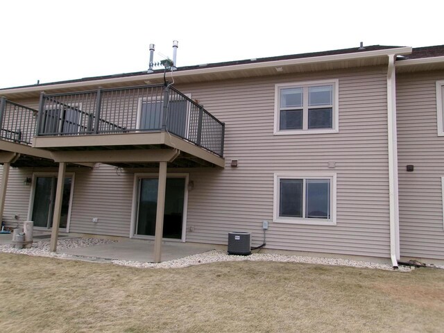 back of house featuring cooling unit, a patio area, and a lawn