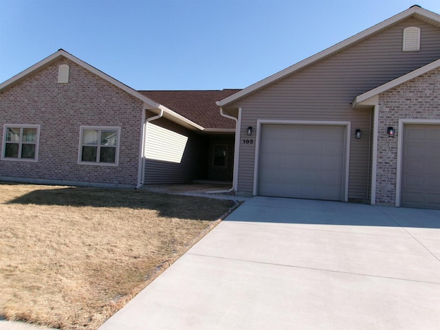 105 Community Dr, Fall River, WI 53932 - single story home featuring a garage, concrete driveway, brick siding, and a front yard