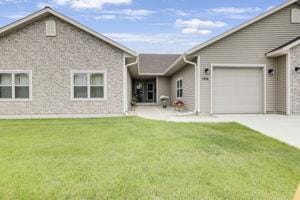 105 Community Dr, Fall River, WI 53932 - rear view of property featuring an attached garage, concrete driveway, and a lawn