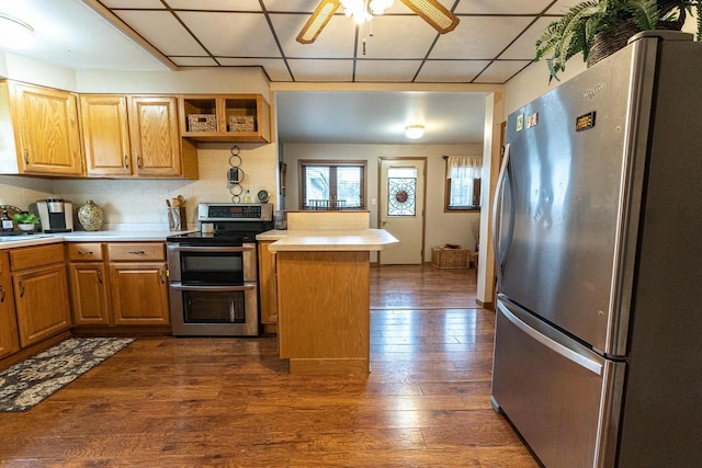 kitchen with appliances with stainless steel finishes, a paneled ceiling, dark hardwood / wood-style flooring, decorative backsplash, and ceiling fan